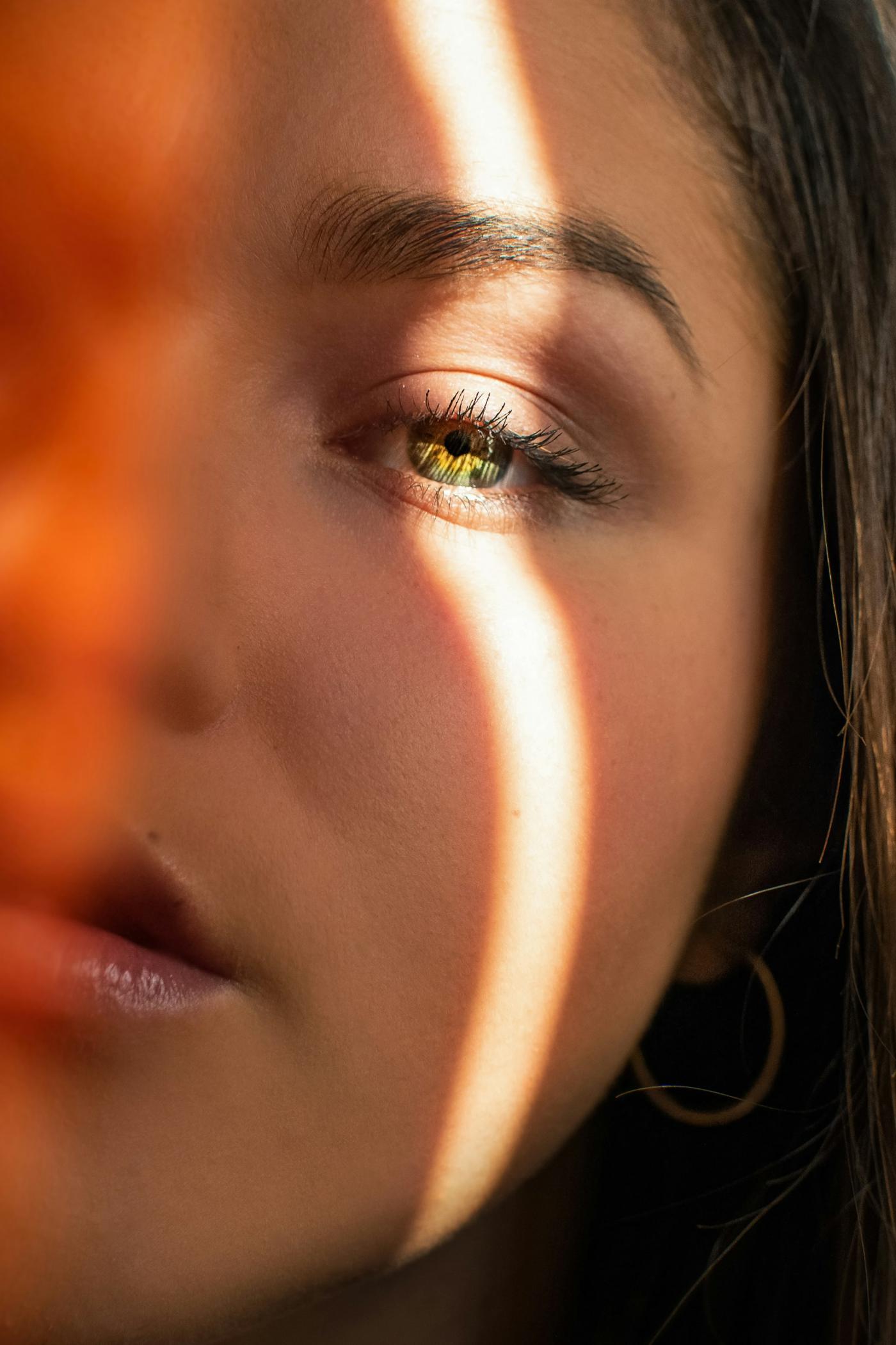 Gezicht in close-up met een warme lichtstreep over oog en wang